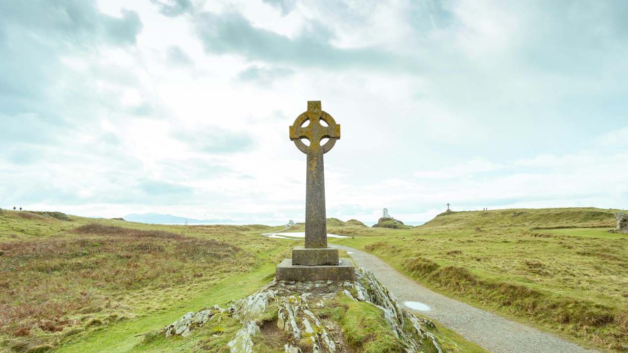 Кельтский крест стоит на возвышение рядом с каменной дорожкой, в поле