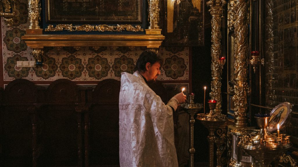 Священник в белой рясе, в церкви