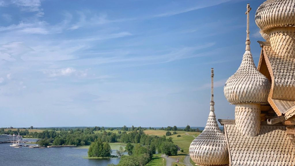 Маковки деревянного храма, на фоне берега реки