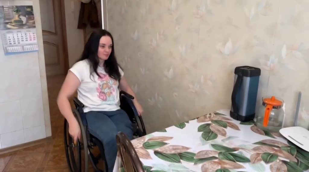Девушка в инвалидной коляске на кухне у стола