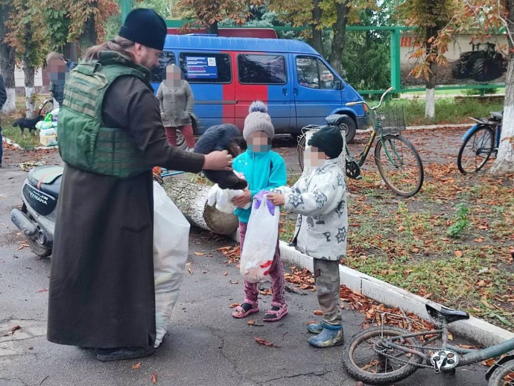 Священник угощает детей конфетами