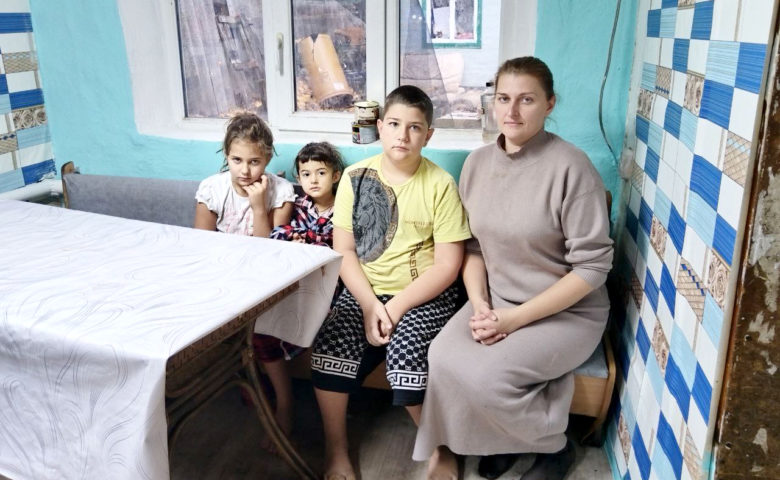 Мама и трое детей сидят на диване у окна