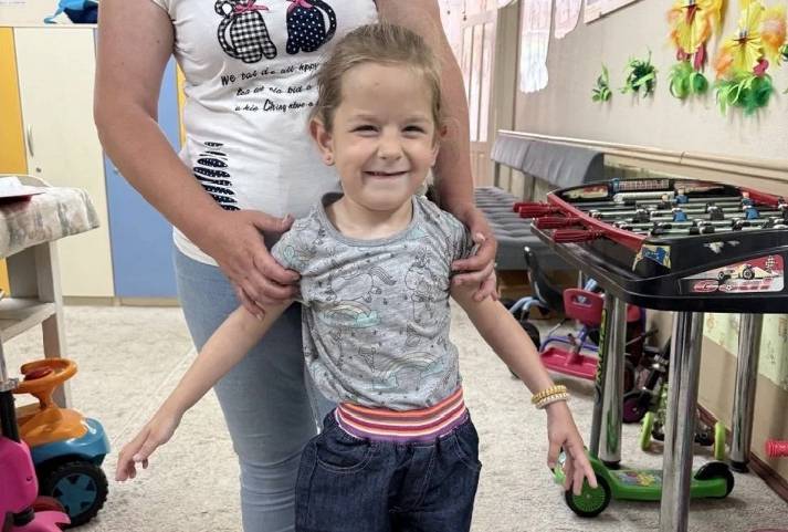 Девочка стоит с поддержкой взрослого