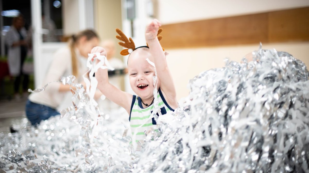 Радостный ребенок среди новогодней мишуры