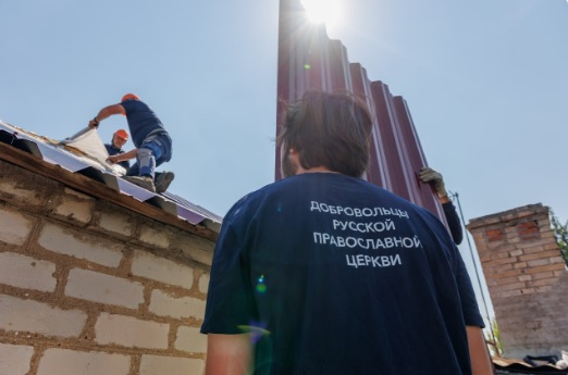 Мужчина из проекта Патриаршей гуманитарной миссии смотрит, как кроют крышу дома