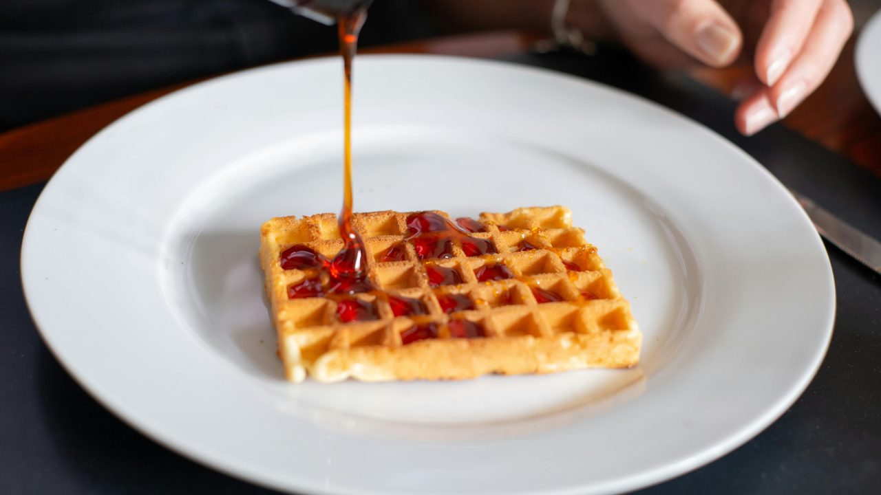 Девушка поливает вафли мёдом