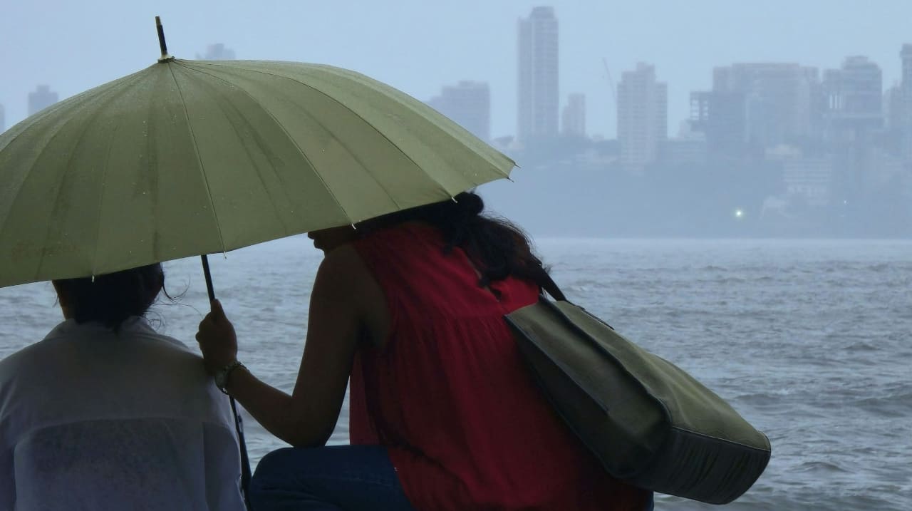 Женщины под зеленым зонтом сидят на берегу реки