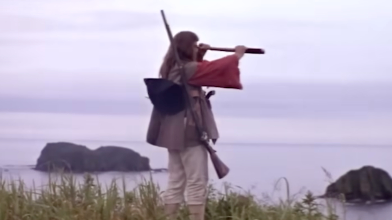 Мужчина на горе смотрит на океан через подзорную трубу