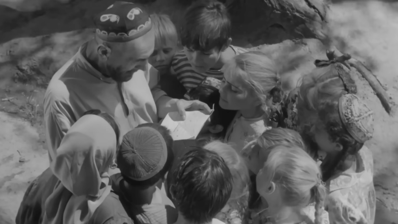 Мужчина стоит и читает письмо в окружении детей