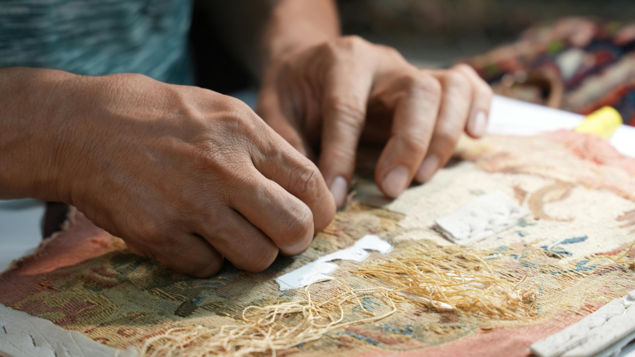 Кисти рук за работой над гобеленом