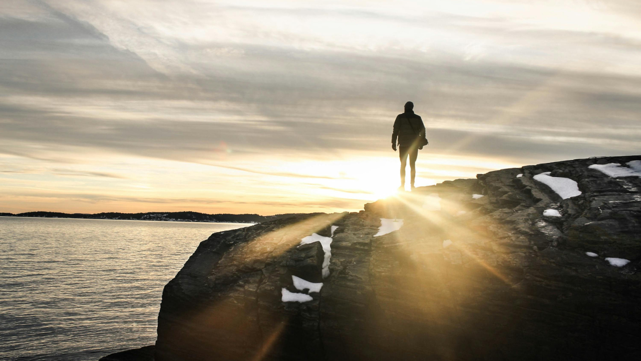 Человек стоит на скале, рядом морем