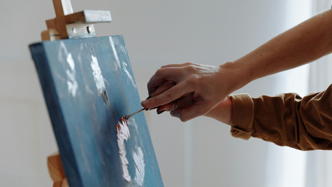 Мужчина пишет картину кистью в женской руке н