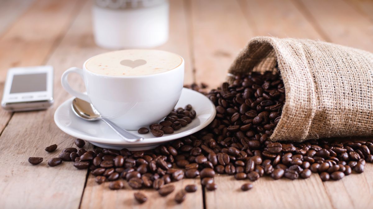 Чашка кофе и рассыпанные кофейные зерна на столе